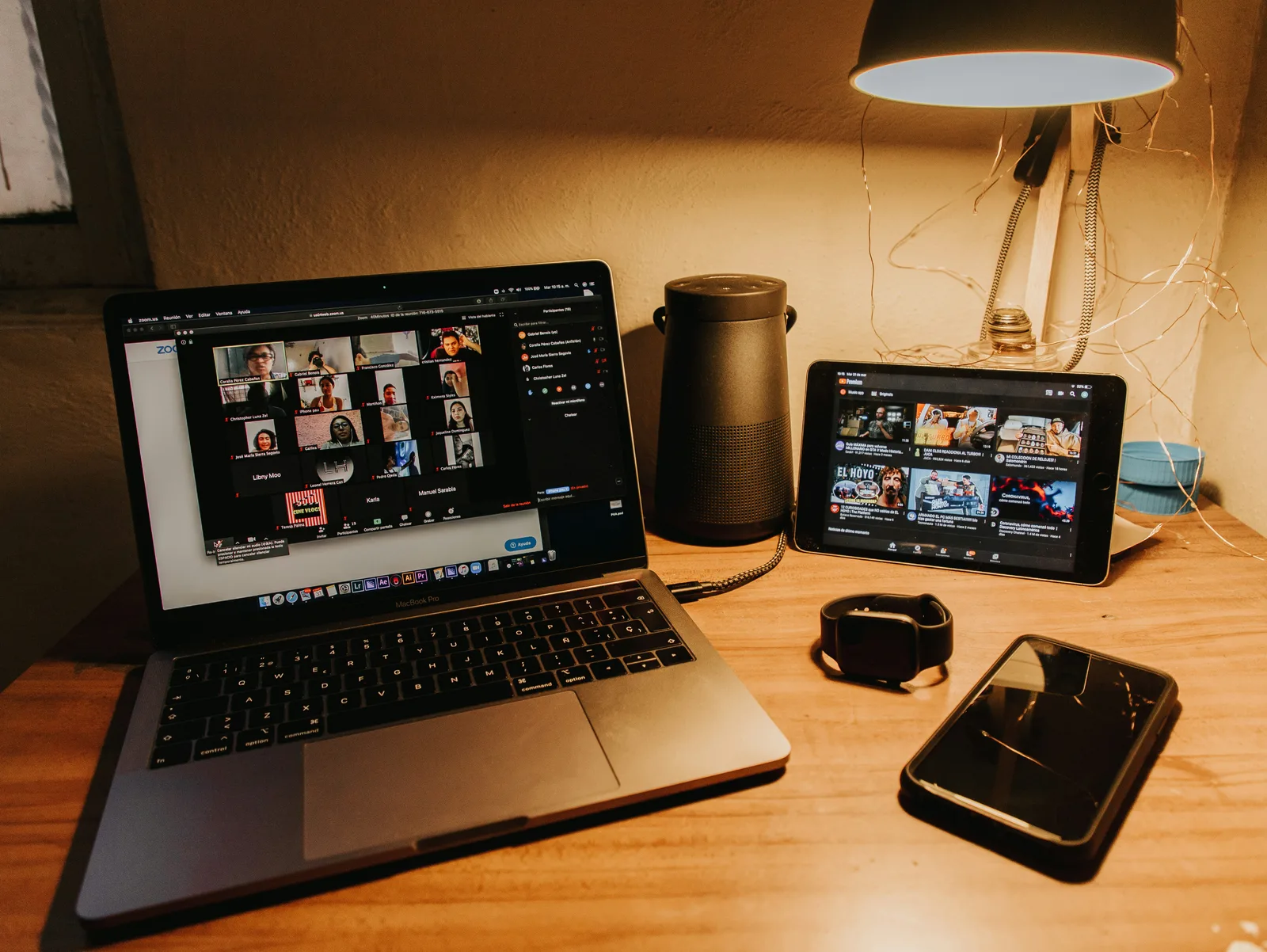 Ordenador portátil con videollamada y varios dispositivos móviles en un escritorio de trabajo remoto.